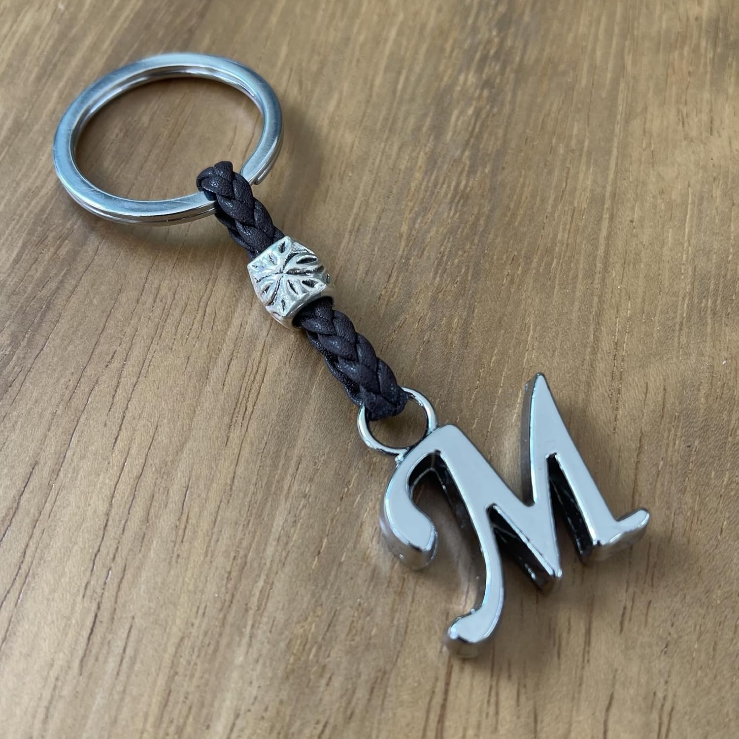 Mano che tiene un portachiavi in cuoio personalizzato con iniziali del nome Aster Alheli.